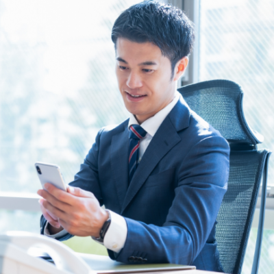 窓際でスマホを操作する男性ビジネスマン