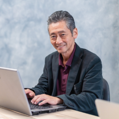 ノートパソコンを操作する笑顔の壮年ビジネスマン